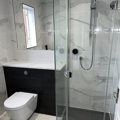 Contemporary bathroom with white marble-effect wall tiles, glass walk-in shower, chrome fixtures, and wall-hung toilet against dark wood-grain paneling.