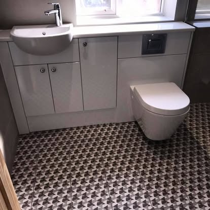 Contemporary bathroom with white built-in vanity, semi-recessed basin, back-to-wall toilet, and bold black, grey, and white geometric patterned floor tiles.